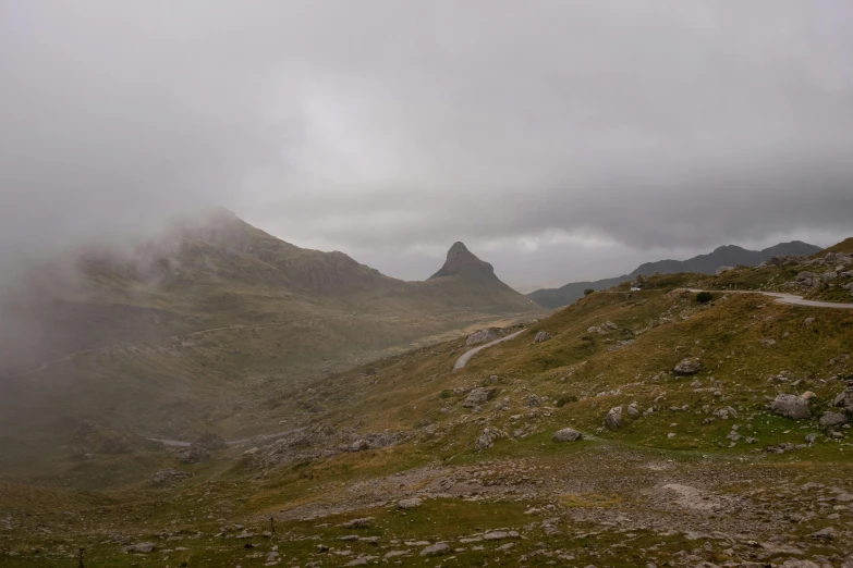 a hill with a road and rock on top in the mountains