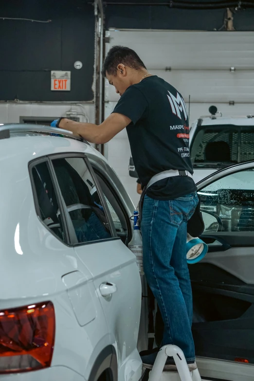 a man sanding a car on top of a white bench