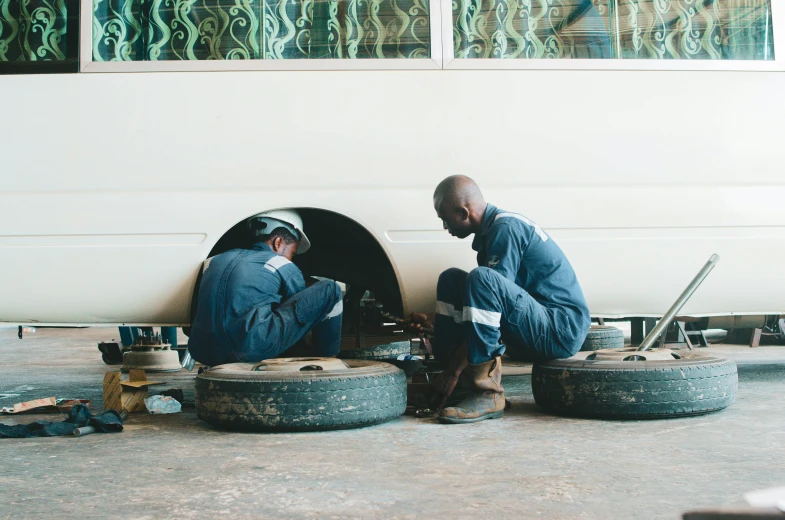 two men sitting on tires looking at soing