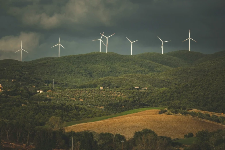 a wind farm on top of a green mountain