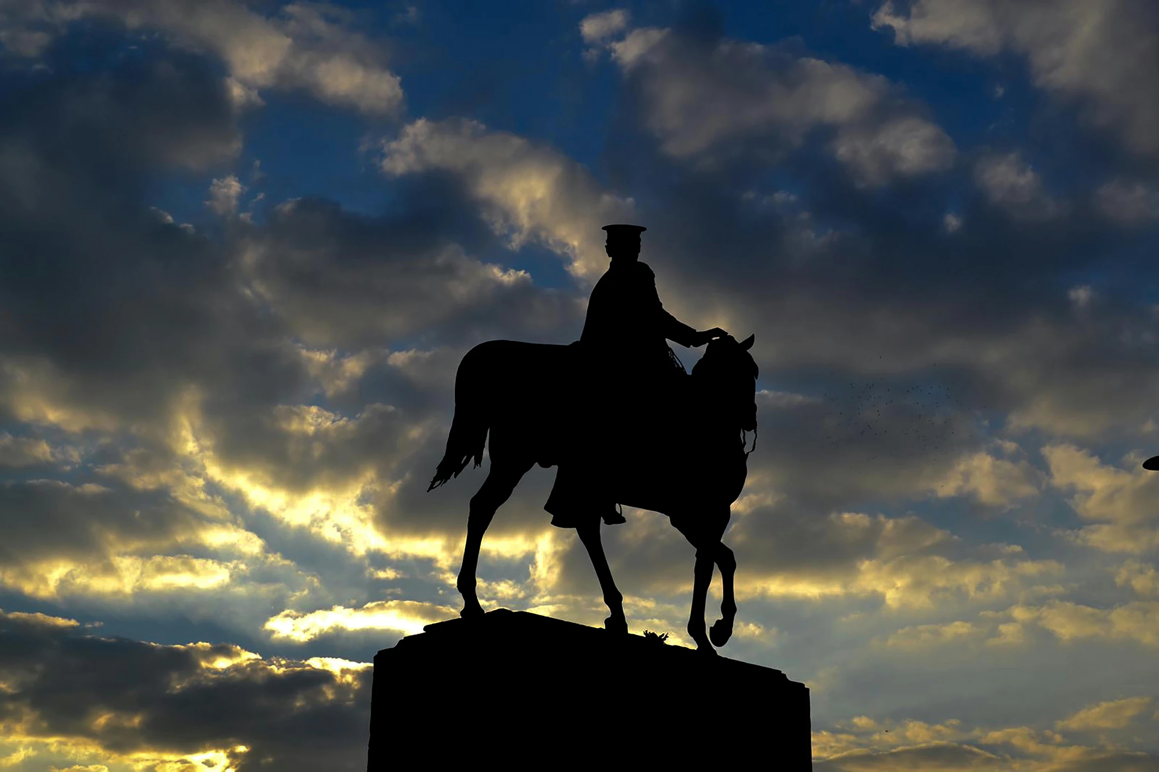 a statue of a cowboy sits atop of a stone column