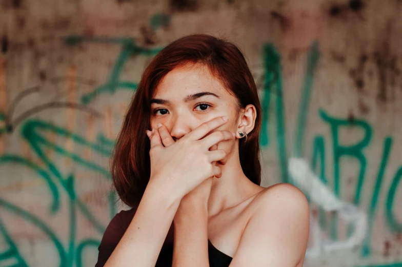 young woman standing in front of a wall covered in graffiti