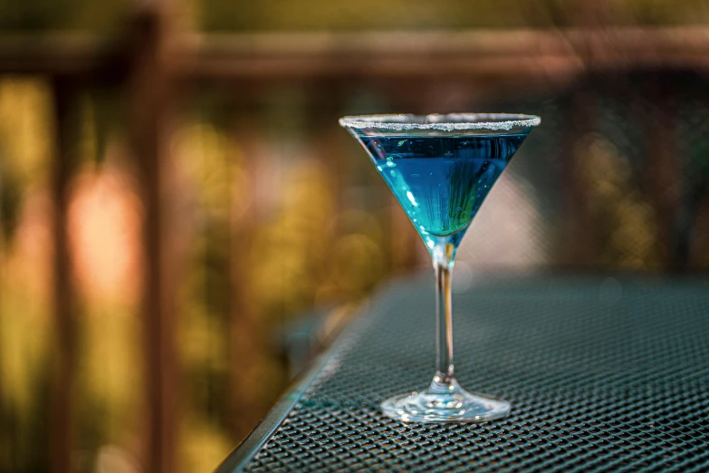 a cocktail drink with a green garnish on top