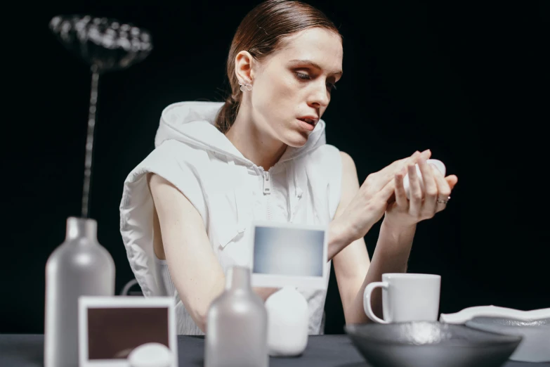 woman in white sitting at table surrounded by coffee mugs