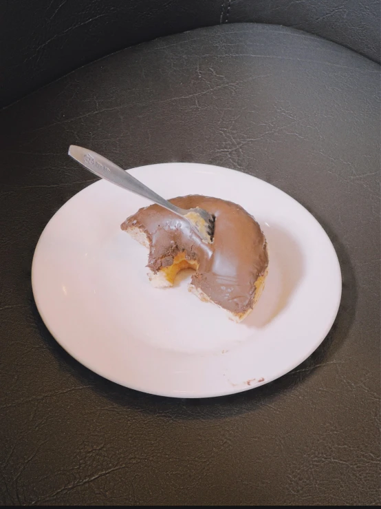 a half eaten doughnut on a white plate with a knife