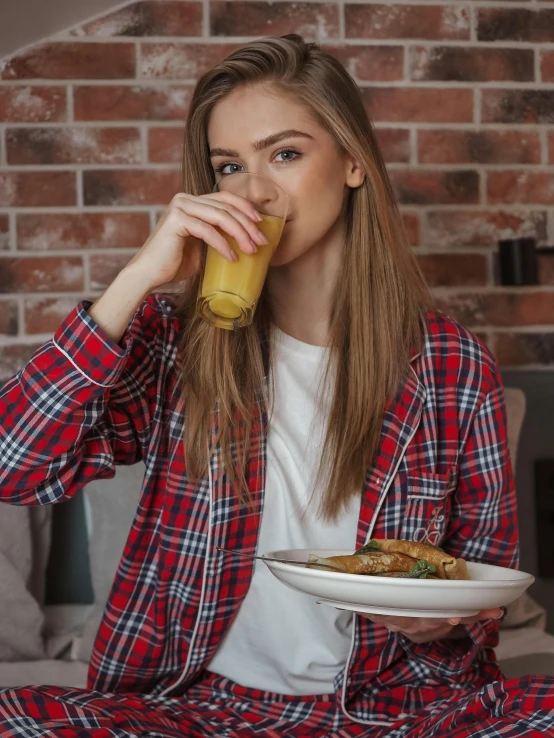 young women in pajamas drinking orange juice and sitting down