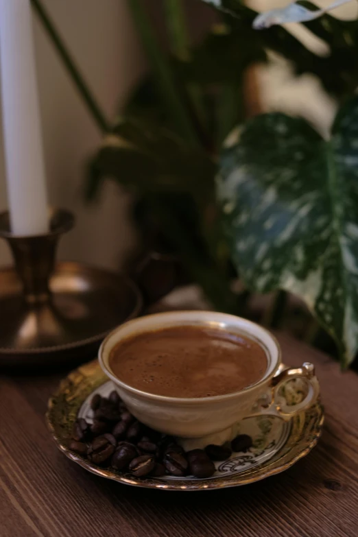 there is a cup of coffee and some beans on the plate