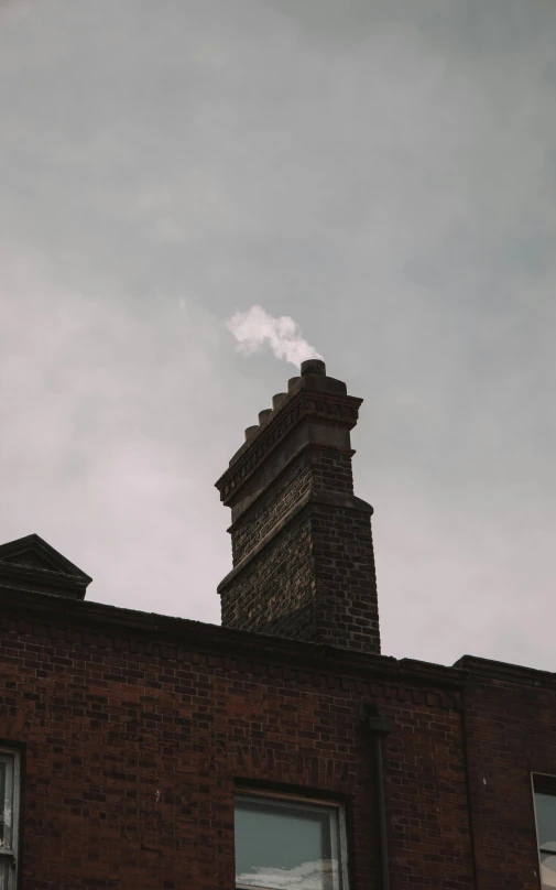 a chimney of an old brick building on a cloudy day