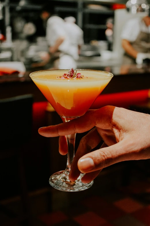 a person holding up a drink in a glass