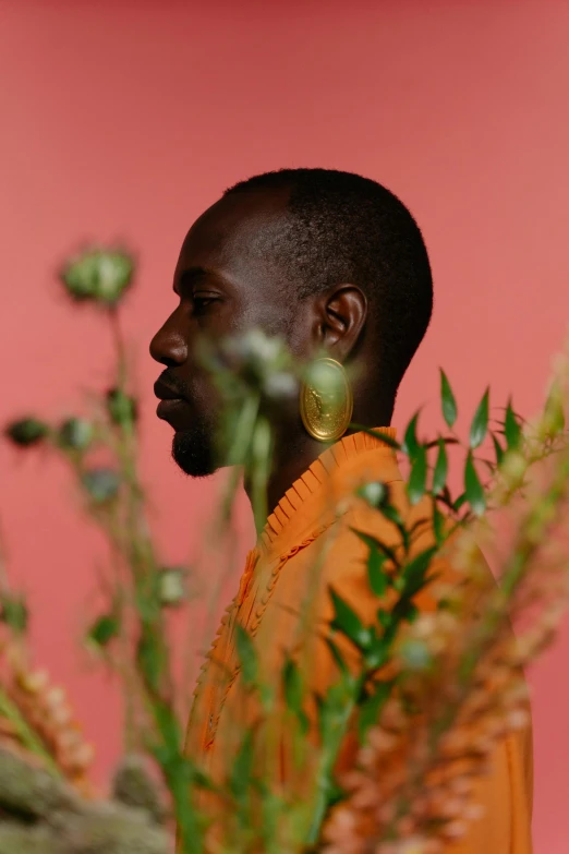 a man in an orange shirt is looking at a plant