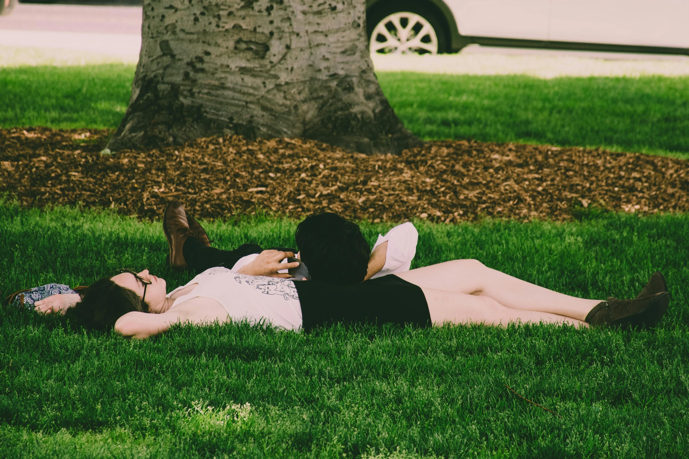 two women sitting down in the grass on the ground