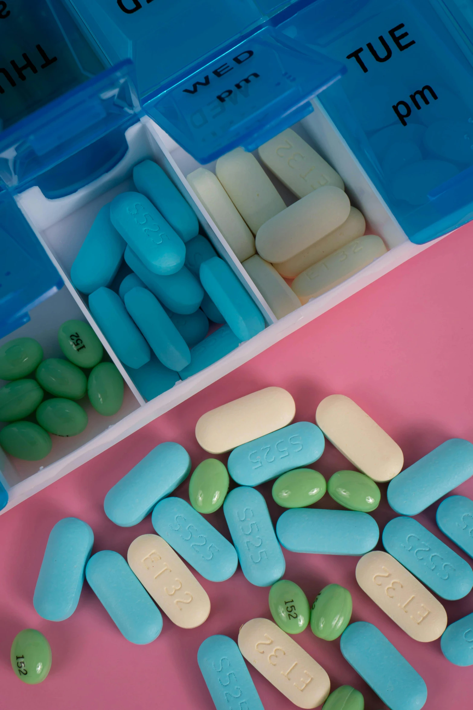 blue and white pills are in containers on a pink table