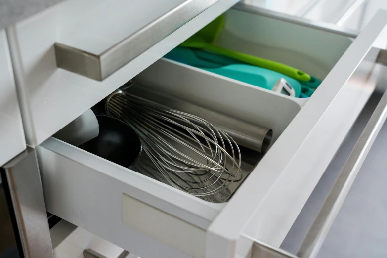 a close up of an empty drawer with a whisk and spoon