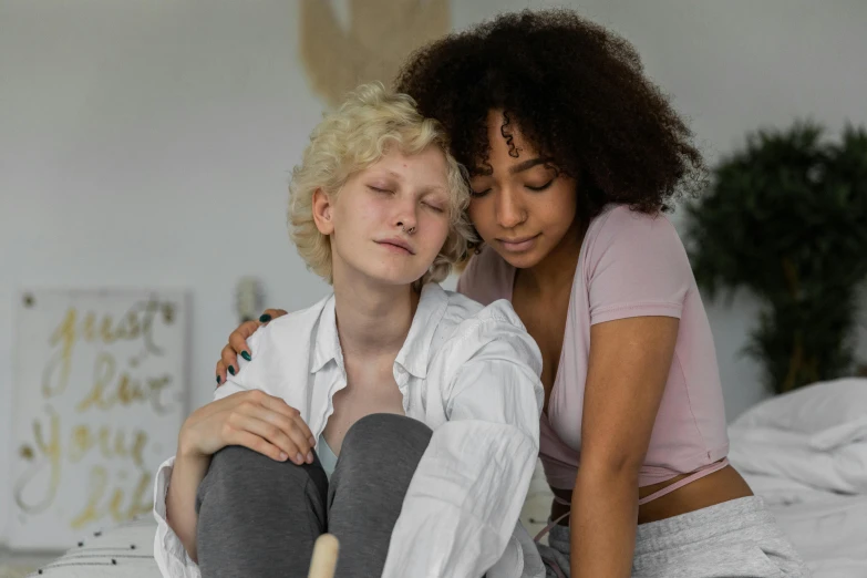 a woman sitting next to another person on a bed