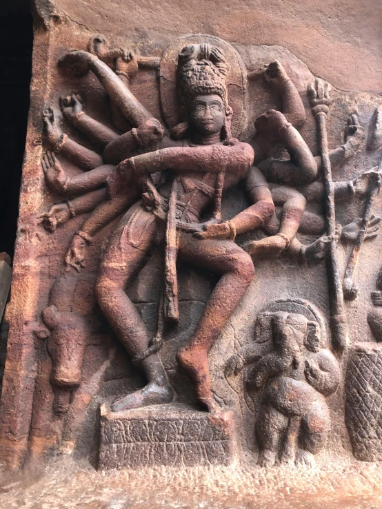 a stone sculpture depicting a god with a spear and two demons in front of him