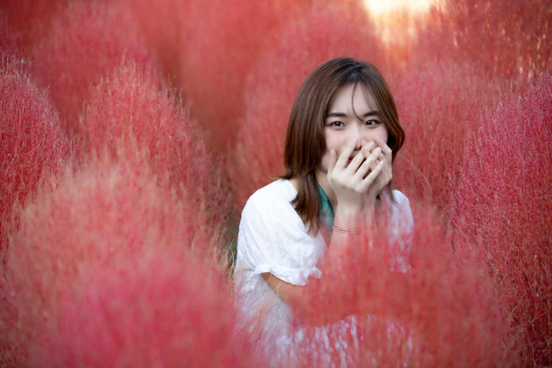 a woman looks through the red bushes in a surreal po