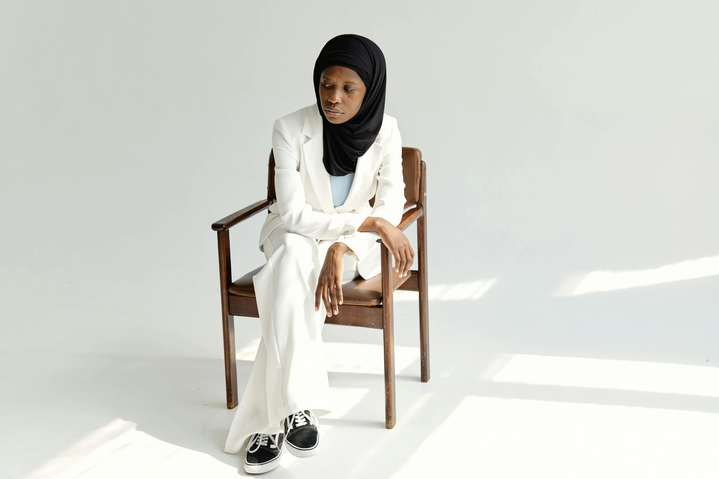 a woman in a white suit sits on a chair