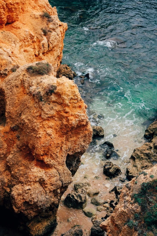 some rocks by a body of water and some white frothy water