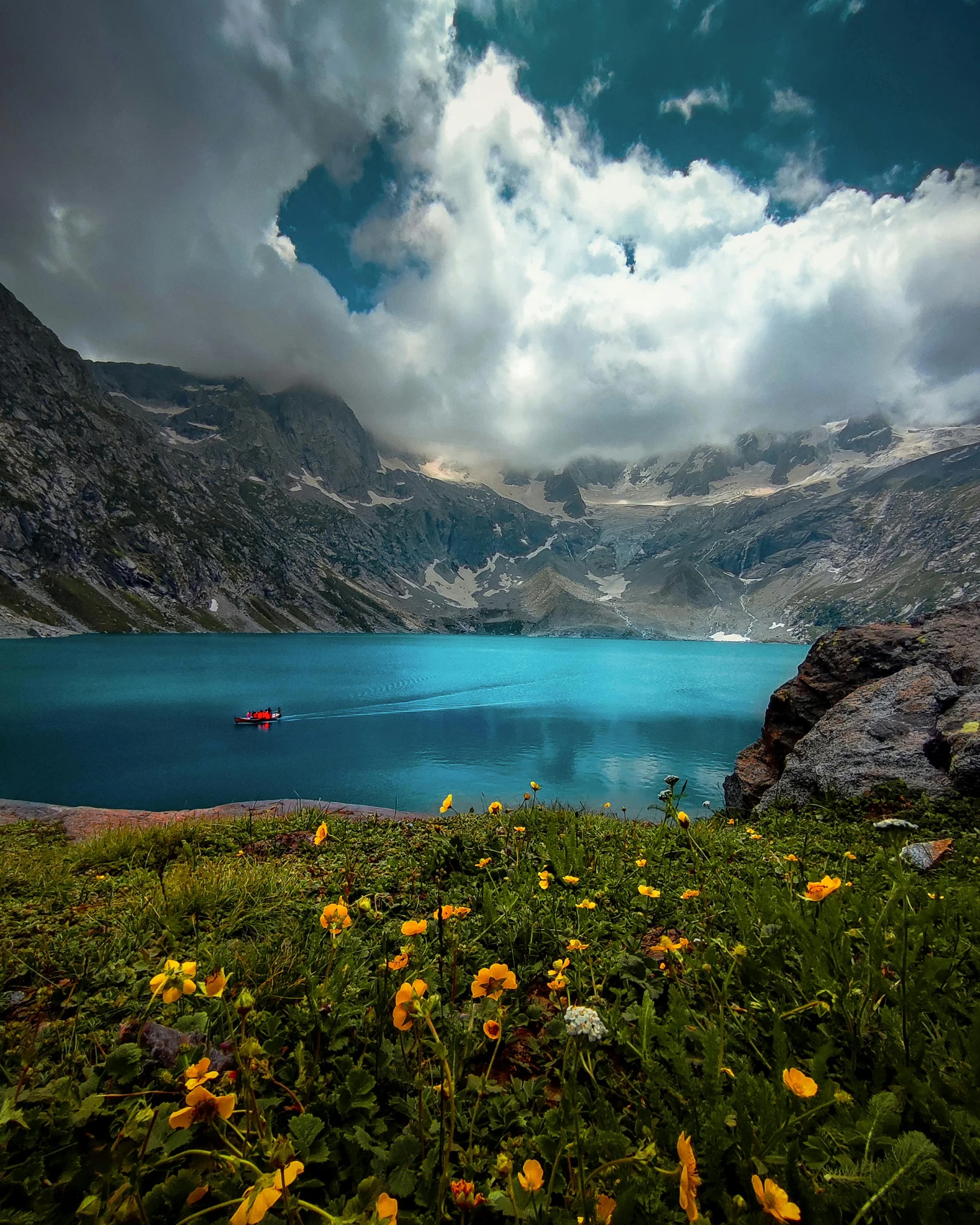 a lake surrounded by mountains next to lush green field