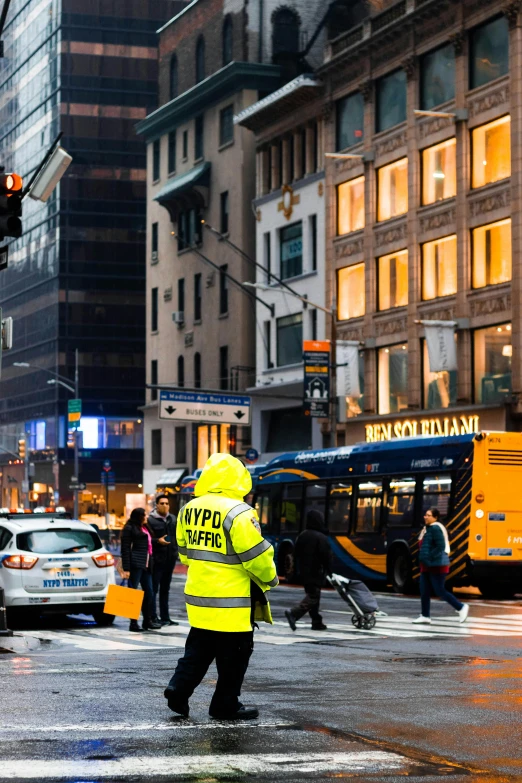 a person in yellow vest crossing street in city