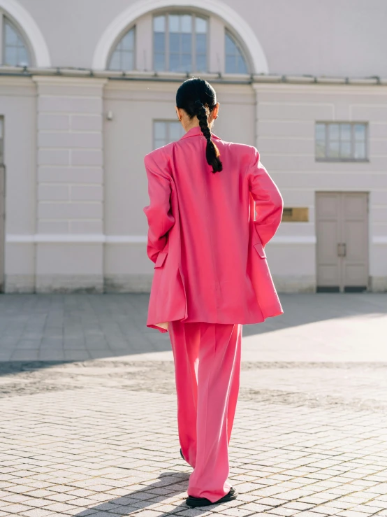 a woman wearing a pink suit with long sleeves and bell sleeves