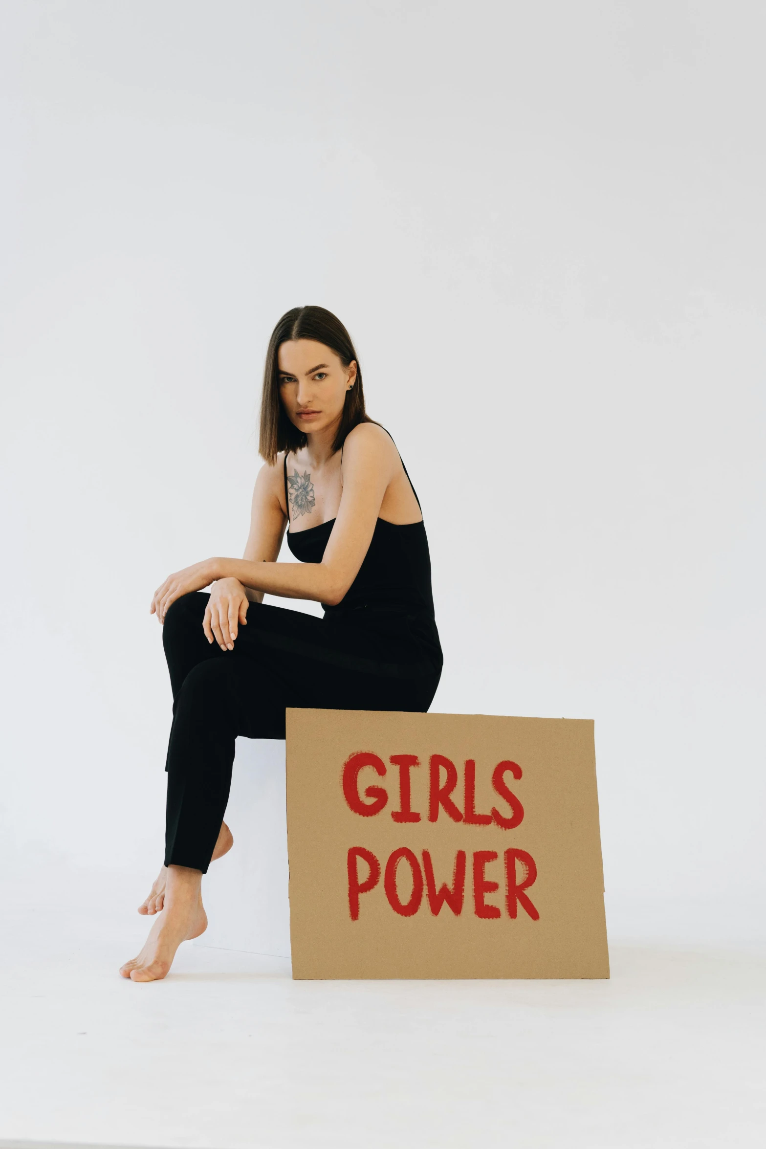 a person sitting down holding a sign that reads girls power