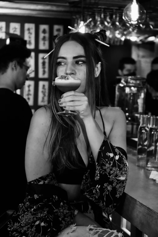 a woman holding a glass while sitting at a bar