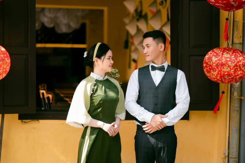 asian couple in traditional clothing standing against an arch