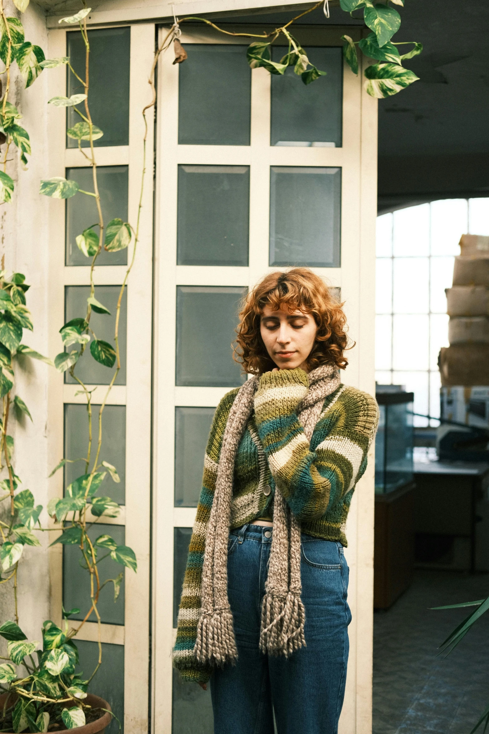 a woman is posing near some plants with a scarf