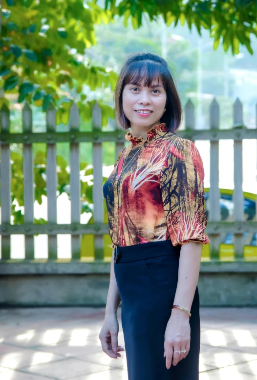 the woman smiles while posing near a fence