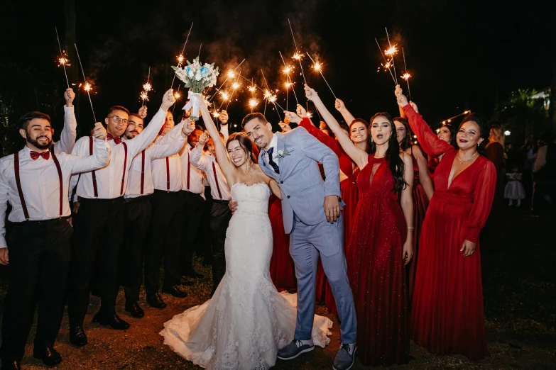 a group of people in red dress holding sparklers at night