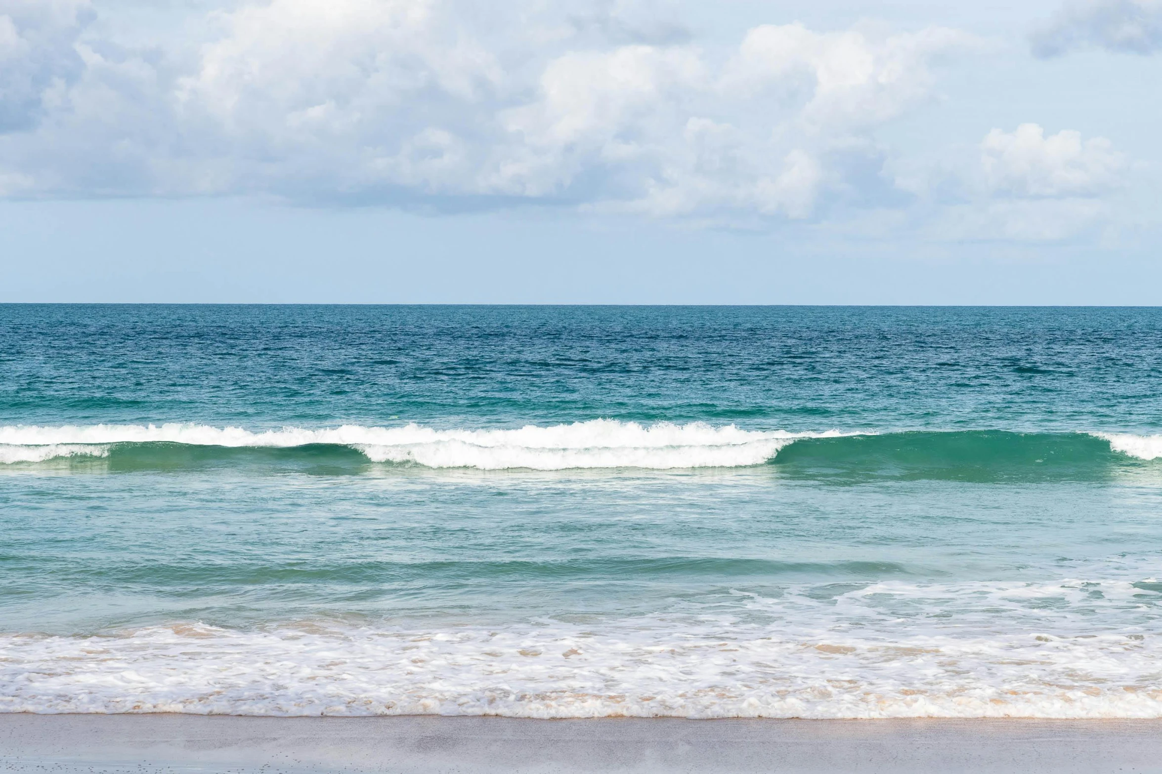 several people standing on the shore line with the ocean in the background