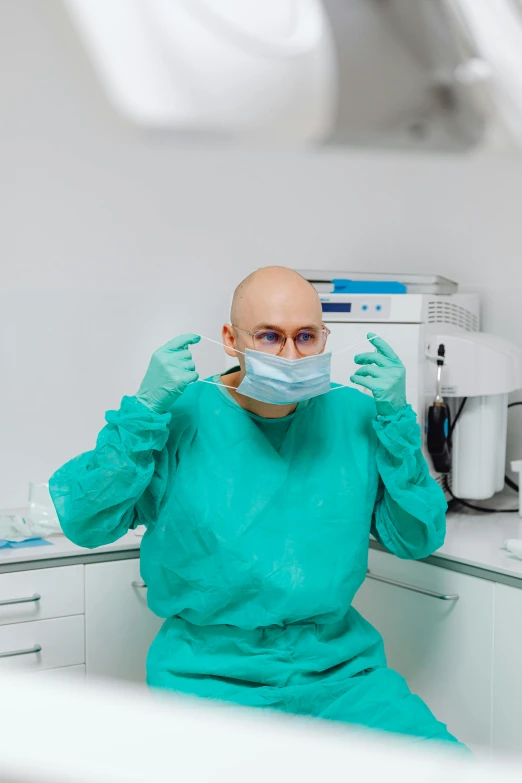 a male in a green scrub suit and glasses