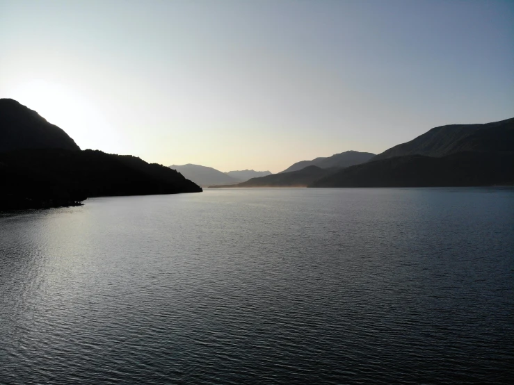 an open body of water with mountains and sky