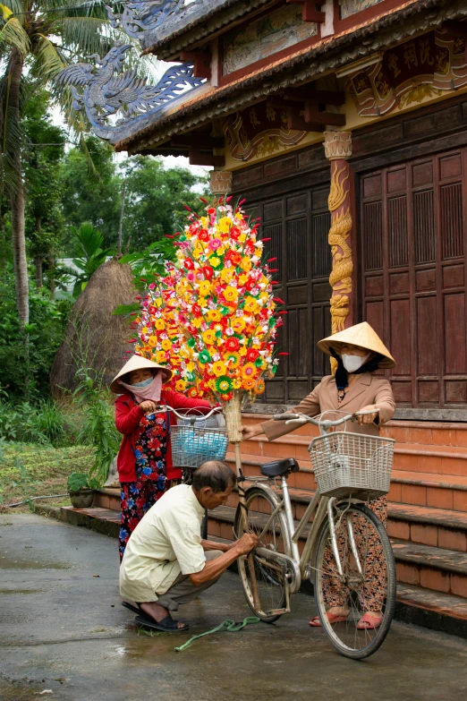 three people are working on a bicycle outside a building