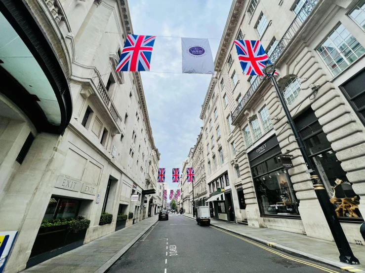 a road with flags on both sides and people walking on the other side