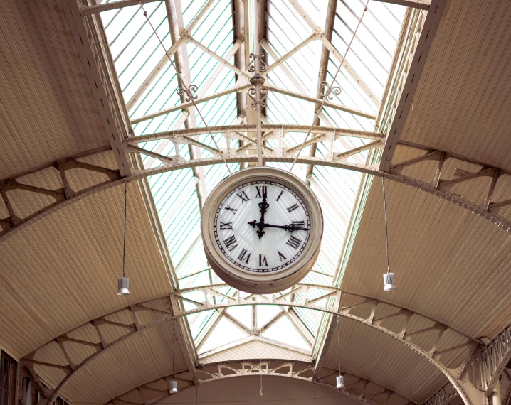 a clock with roman numerals sitting below a glass ceiling