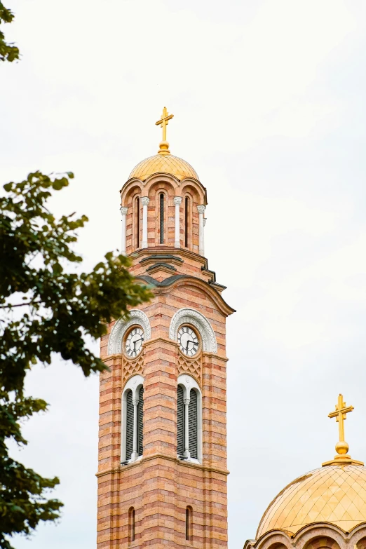 the top of a bell tower with a cross and gold roof