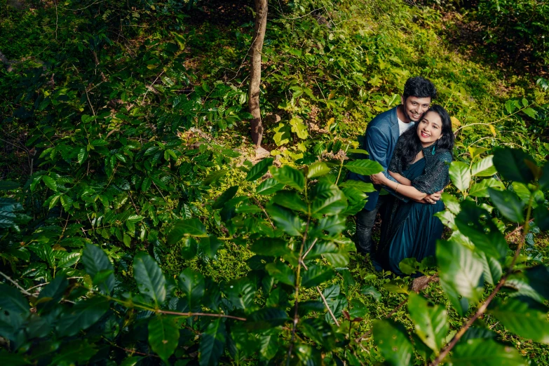 a couple standing in the bushes at their engagement po