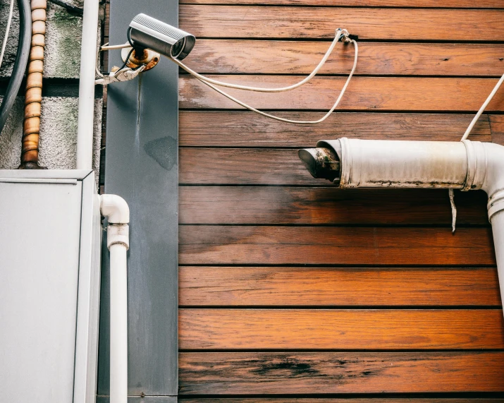 the two cameras are on top of the wall next to the pipes