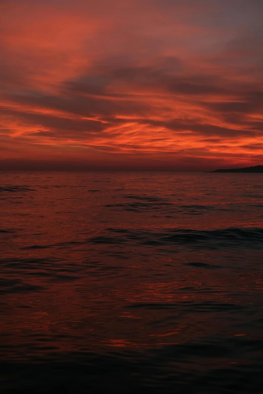 a red and blue sky filled with lots of clouds over water