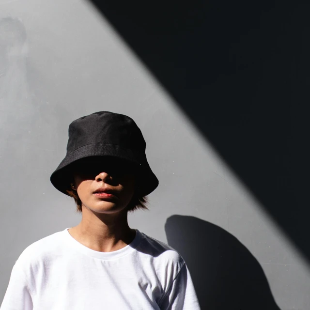 a person is wearing a hat and standing by a wall