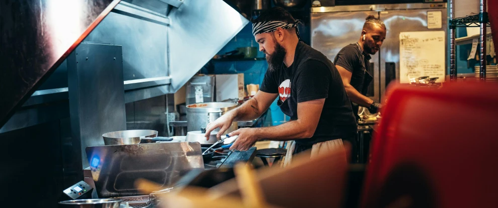 two men are standing in the kitchen working on soing