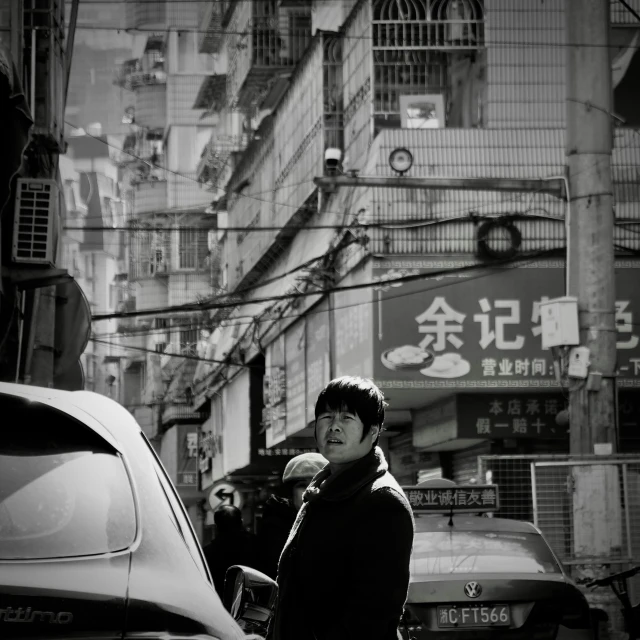 a man stands next to a car near a tall building