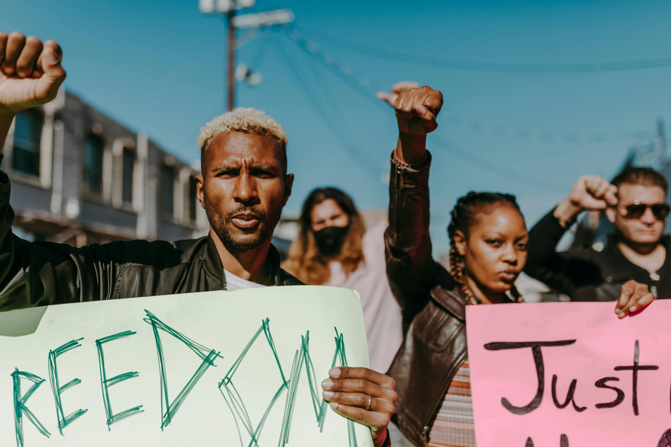 man holding up a sign with writing on it while other people hold up hands