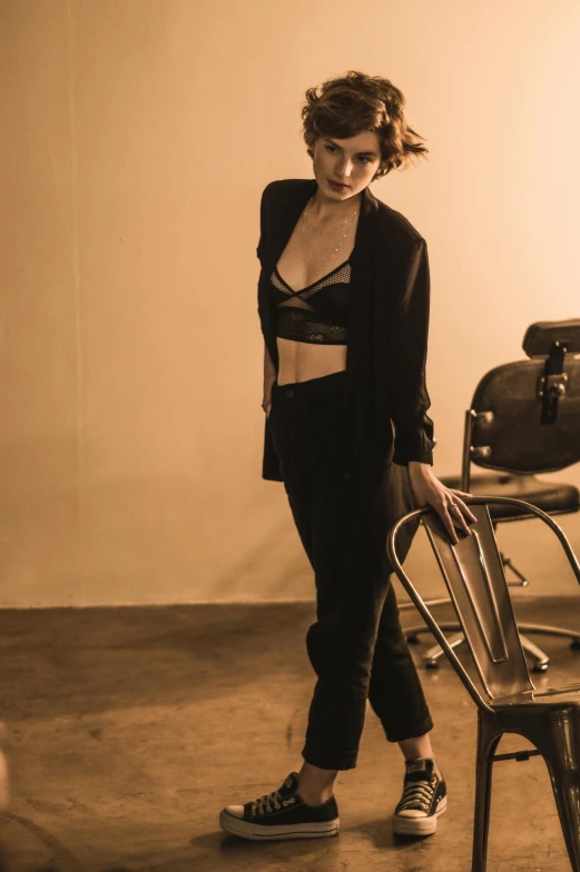 a woman in black top standing near chair with metal legs