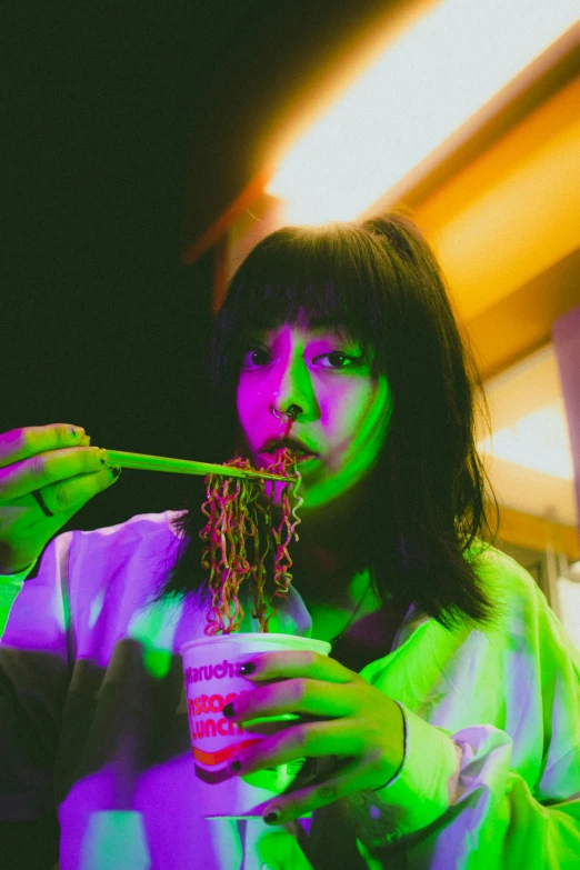 a woman holding a drink while wearing neon lights