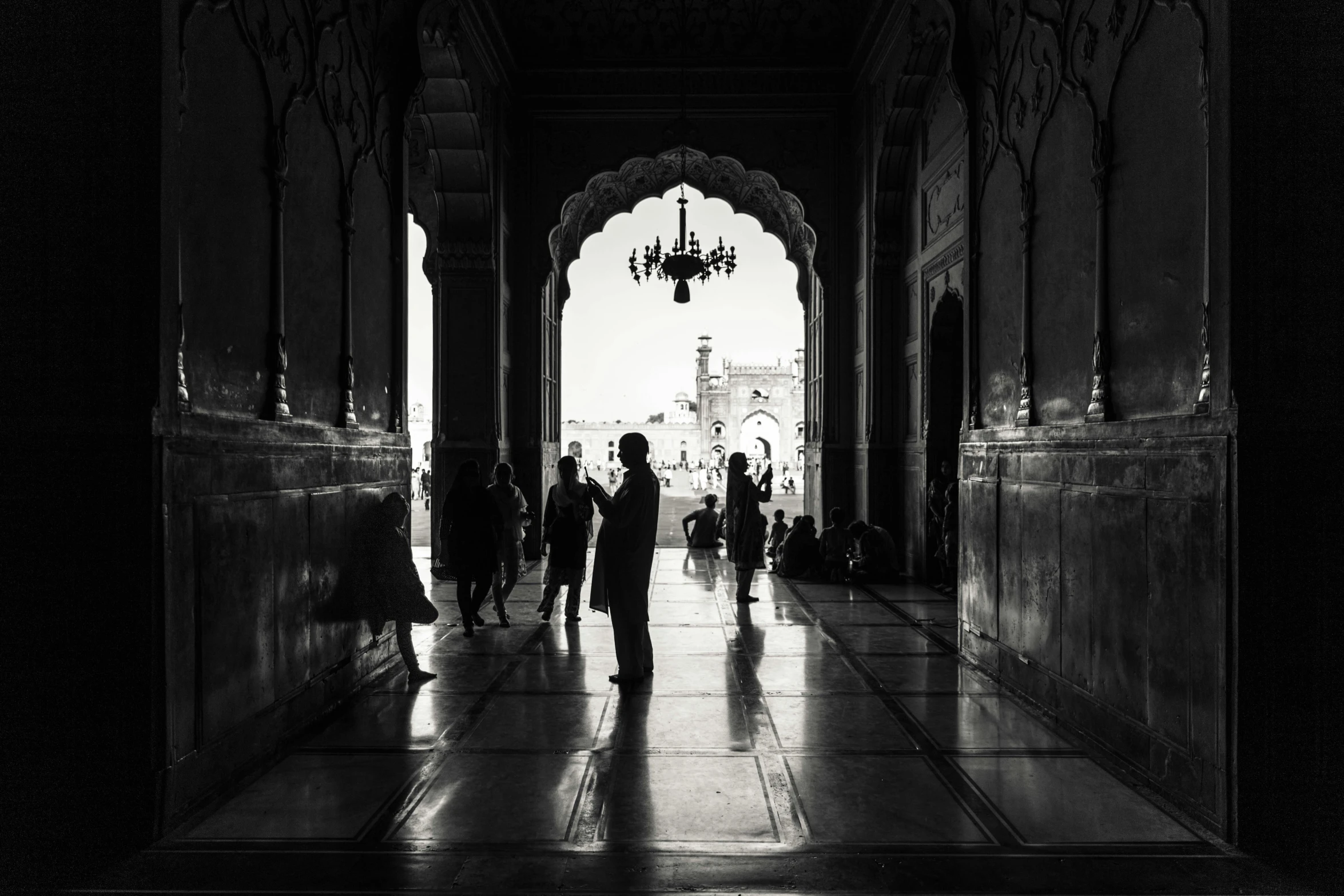 some people are standing under an archway looking towards a light