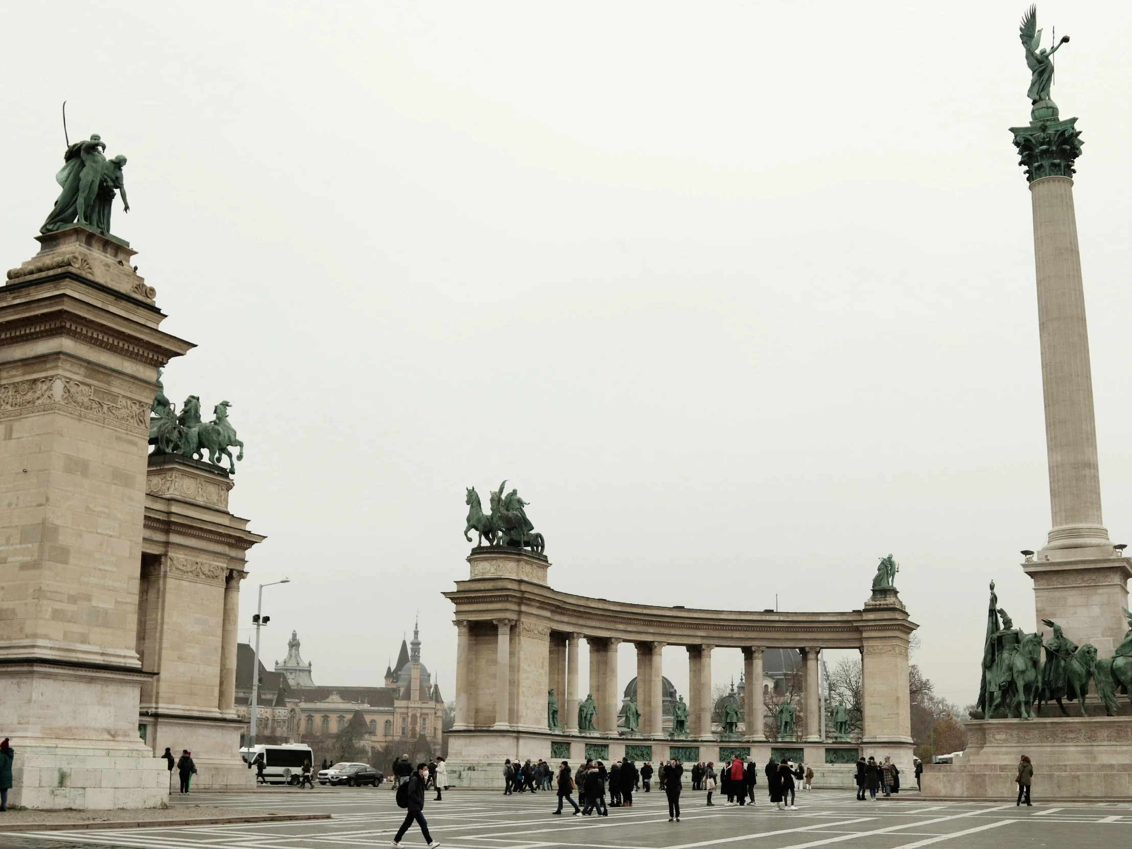 people walking in the streets of a park and statues