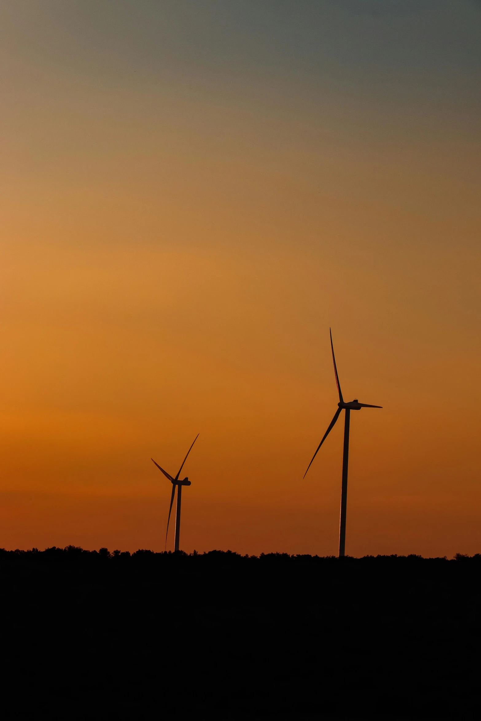 several windmills are silhouetted against a sunset sky